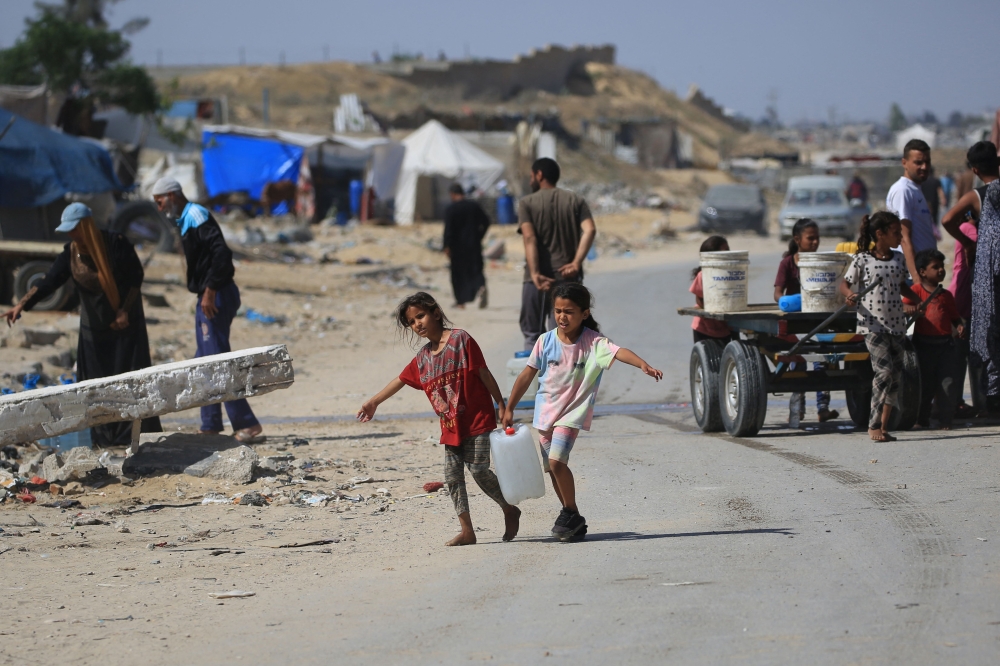 Displaced Palestinian children carry water in a makeshift camp in Khan Yunis in the southern Gaza Strip on May 24, 2024. Photo by Eyad BABA / AFP.