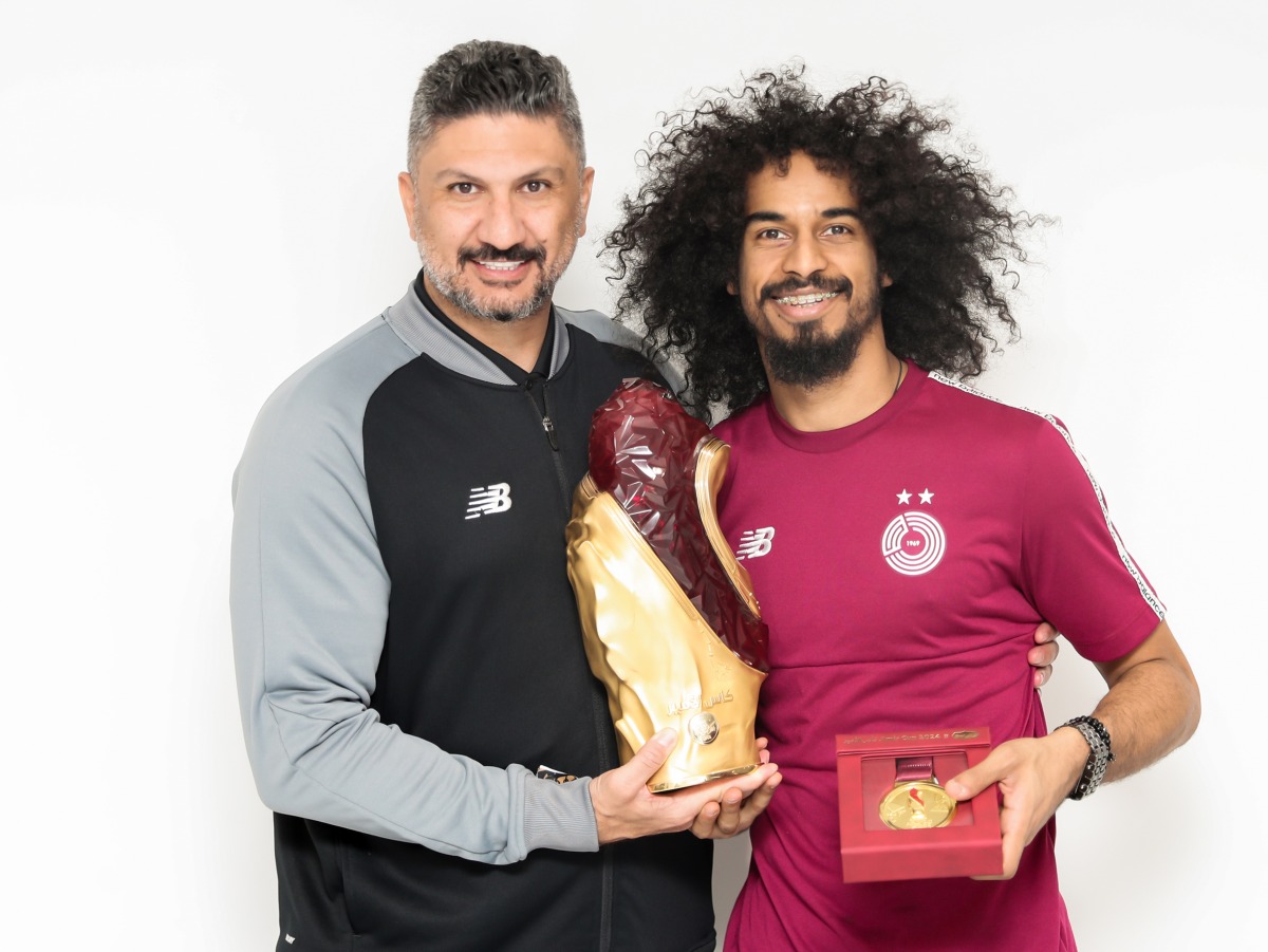 Al Sadd coach Wesam Rizk and striker Akram Afif pose with the Amir Cup trophy.