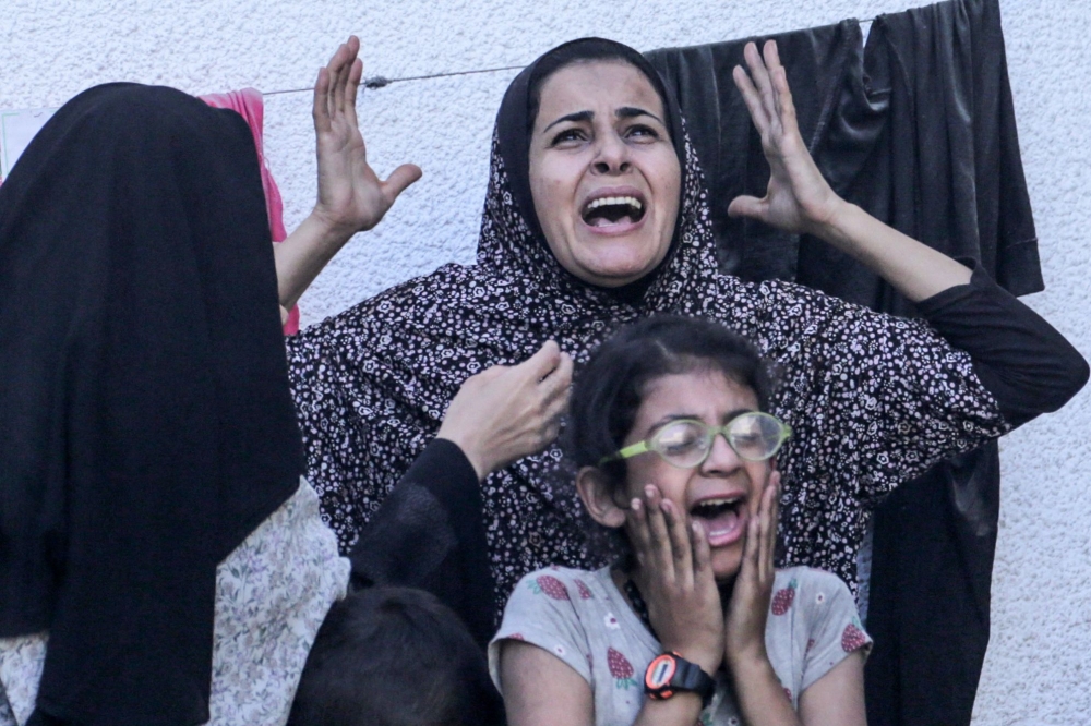 Palestinians react after an Israeli strike on a building in Nuseirat on May 25, 2024. (Photo by Bashar Taleb / AFP)