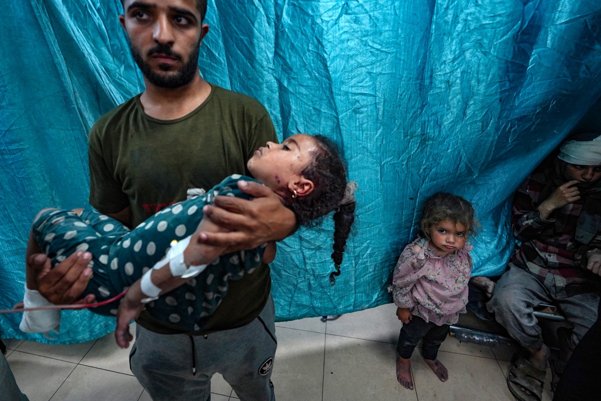 A man carries a girl injured in Israeli strikes on Bureij, at the Al-Aqsa Martyrs Hospital in Deir al-Balah in the central Gaza Strip on May 25, 2024. Photo by Bashar TALEB / AFP