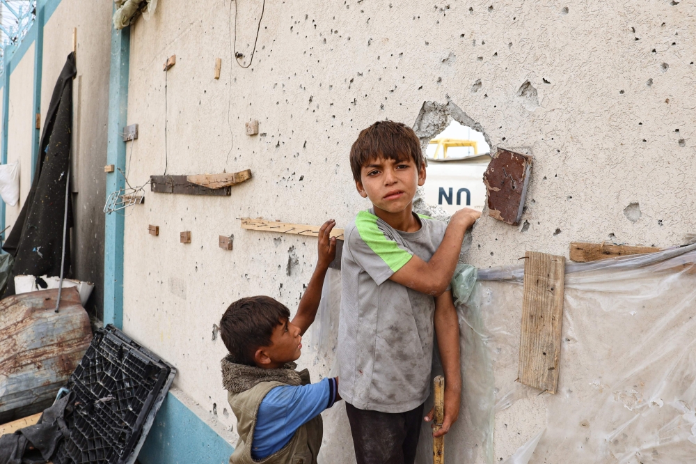 Palestinian boys stand near a damaged structure at the site of an Israeli strike a day earlier on a camp for internally displaced people in Rafah in the southern Gaza Strip on May 28, 2024.(Photo by Eyad Baba / AFP)