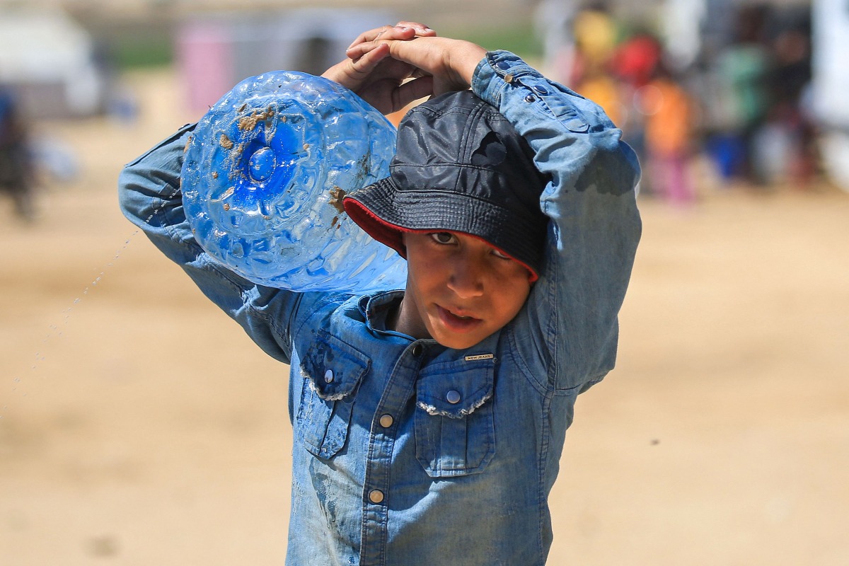 A Palestinian boy carries a water container in Rafah, in the southern GAZA Strip, on May 31, 2024. (Photo by Eyad BABA / AFP)
