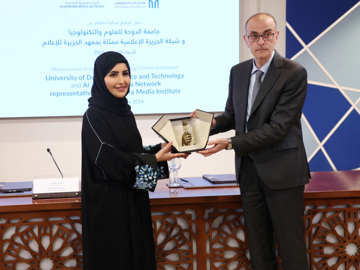 Director of Aljazeera Media Institute Eman Al Amri and Dean of the College of Computing and Information Technology at UDST Zakaria Maamar exchanging documents after signing an agreement.