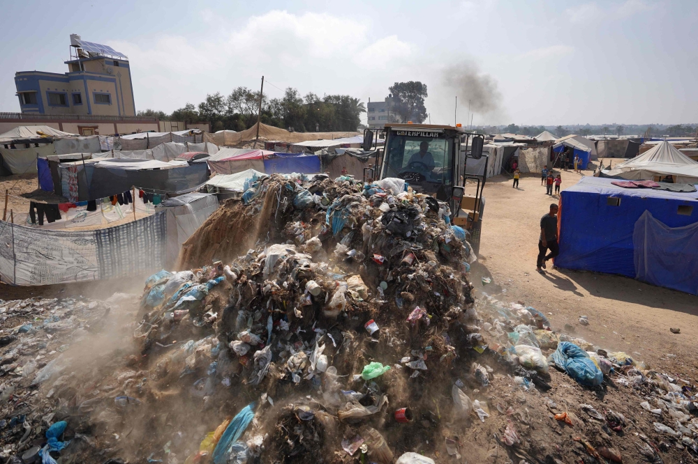 A bulldozer removes piles of garbage at a camp for internally displaced Palestinians in Deir al-Balah in the central Gaza Strip on June 3, 2024. (Photo by Bashar Taleb / AFP)

