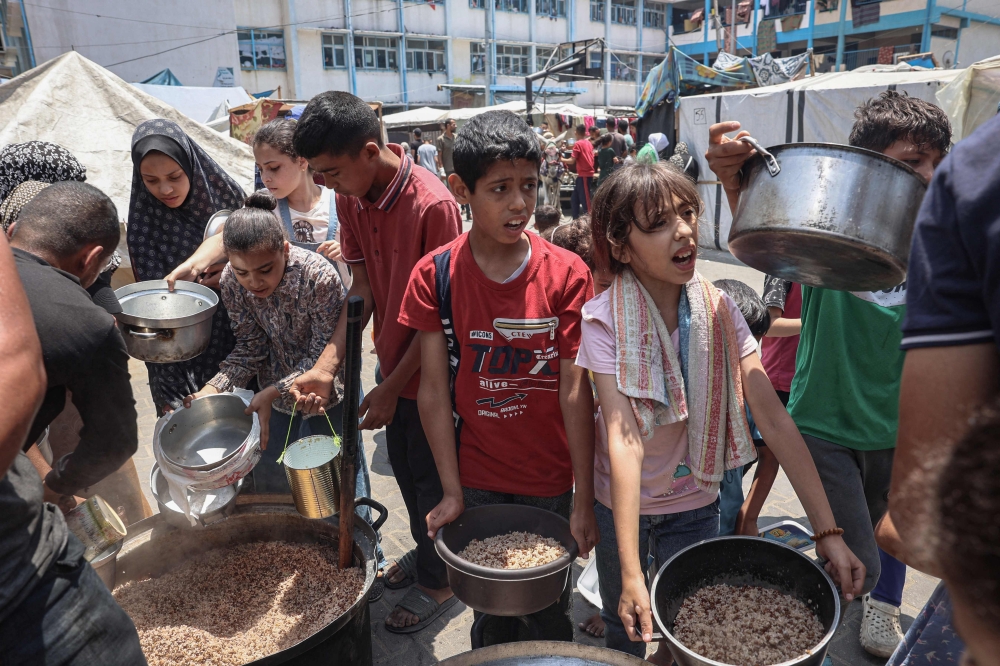 Palestinians queue for meal rations at a communal food distribution point in al-Bureij refugee camp in the besieged Gaza Strip on June 3, 2024. Photo by Eyad BABA / AFP