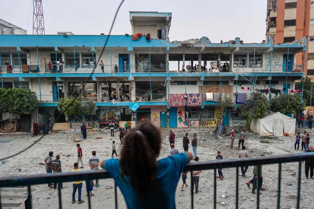 A Palestinian girl watches as others check a UN-school housing displacing people that was hit during Israeli bombardment in Nuseirat, in the central Gaza Strip, on June 6, 2024. (Photo by Bashar Taleb / AFP)
