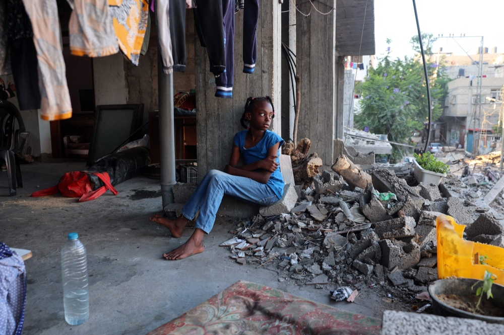 A displaced Palestinian girl sits in a damaged building in which she took refuge in al-Bureij refugee camp in the central Gaza Strip on June 12, 2024. (Photo by Eyad Baba / AFP)