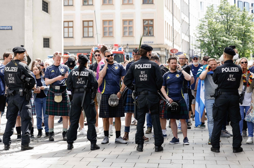 Police face supporters of Scotland's national soccer team wearing kilts as they block the way to the central square Marienplatz after it is too crowded by supporters ahead of the UEFA Euro 2024 Group A football match between Germany and Scotland in Munich on June 14, 2024. (Photo by Michaela STACHE / AFP)