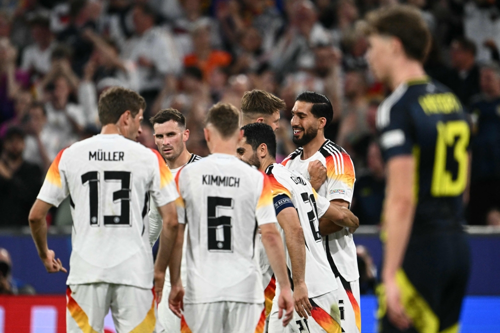 Germany's midfielder #25 Emre Can (R) celebrates with teammates after scoring his team's fifth goal during the UEFA Euro 2024 Group A football match between Germany and Scotland at the Munich Football Arena in Munich on June 14, 2024. Photo by Fabrice COFFRINI / AFP.