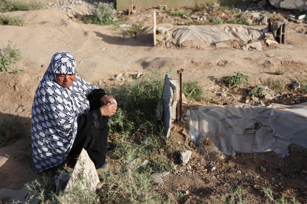 A Palestinian woman reacts near the shallow grave of a relative in the eastern al-Tuffah neighbourhood of Gaza City on June 16, 2024. (Photo by Omar Al Qattaa / AFP)