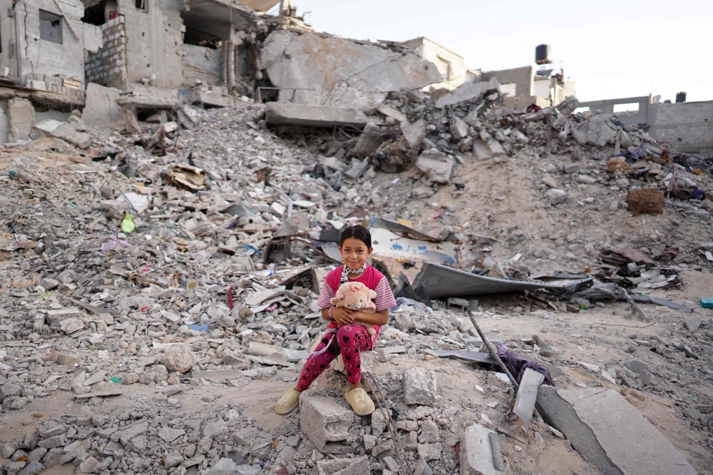 A Palestinian girl, dressed in new clothes, sits amid the rubble of a destroyed building as she celebrate the Eid al-Adha in Khan Yunis in the southern Gaza Strip, on the first day of the Muslim holiday marking the end of the hajj pilgrimage to Makkah, on June 16, 2024. (Photo by Bashar TALEB / AFP)
