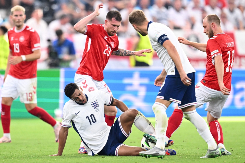 England's midfielder #10 Jude Bellingham reacts after being tackled by Denmark's midfielder #10 Christian Eriksen (right) during the UEFA Euro 2024 Group C football match between Denmark and England at the Frankfurt Arena in Frankfurt am Main on June 20, 2024. (Photo by Kirill Kudryavtsev / AFP)
 