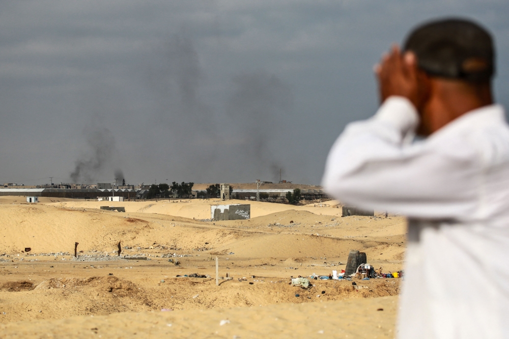 Smoke from Israeli bombardment billows in the background near an area previously housing displaced Palestinians leaving Rafah towards Khan Yunis on June 20, 2024, in the southern Gaza Strip. (Photo by Bashar TALEB / AFP)
