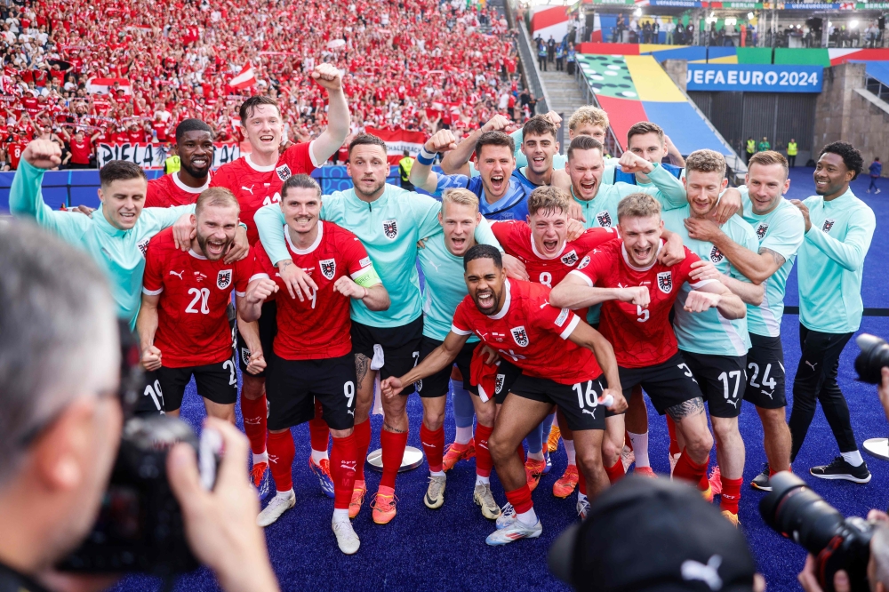 Austria's players pose for a picture as they celebrate at the end of the UEFA Euro 2024 Group D football match between Poland and Austria at the Olympiastadion in Berlin on June 21, 2024. (Photo by Axel Heimken / AFP)