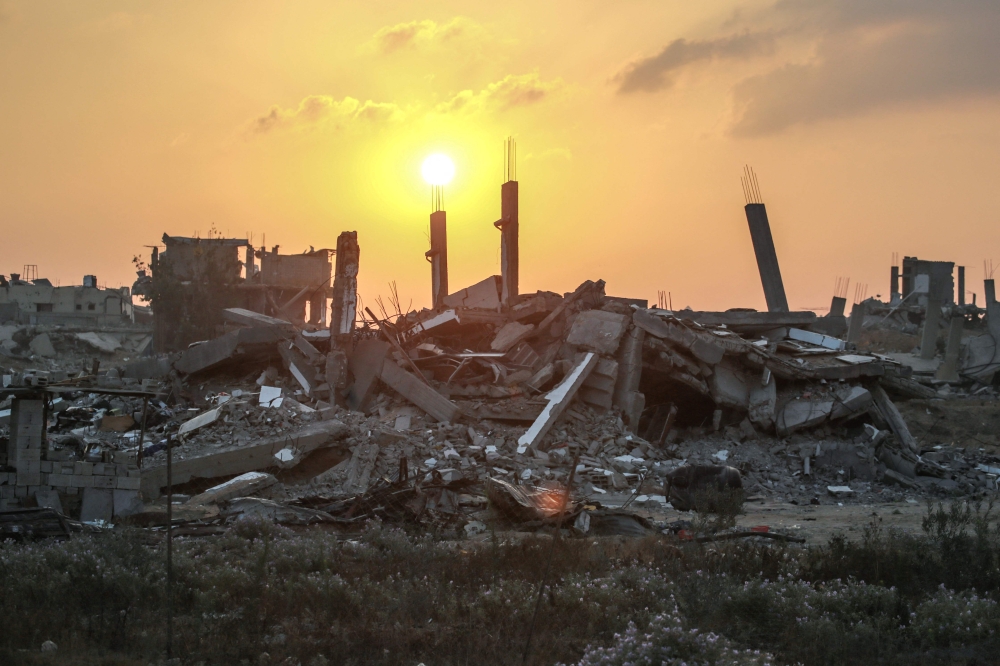 The sun rises over destroyed buildings in Khan Yunis, in the southern Gaza Strip on June 22, 2024. (Photo by Bashar Taleb / AFP)