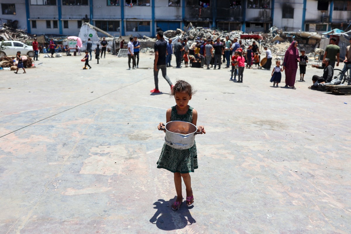 A child carries food at a UN Relief and Works Agency for Palestine Refugees (UNRWA) school in the Jabalia camp for Palestinian refugees in the northern Gaza Strip on June 17, 2024. Photo by Omar AL-QATTAA / AFP.