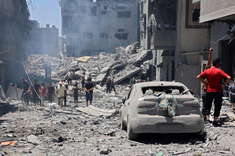 People inspect the damage next to a building destroyed during Israeli bombardment at al-Shati refugee camp in Gaza City on June 22, 2024. (Photo by Omar Al-Qattaa / AFP)