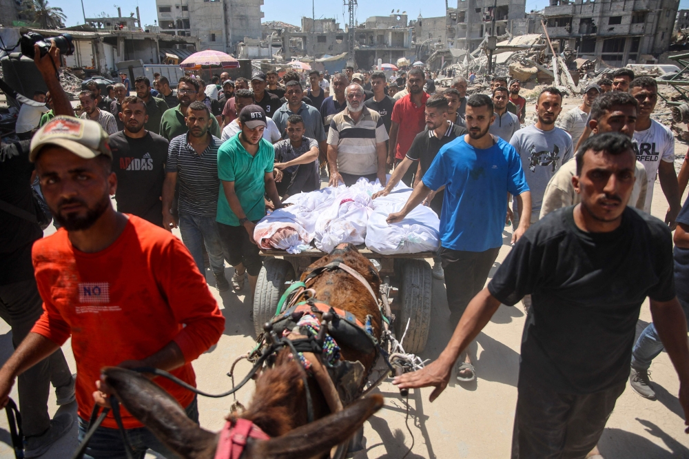 Palestinians transport the bodies of loved ones killed during Israeli bombardment for burial in al-Tuffah neighbourhood in Gaza City on June 22, 2024. (Photo by Omar AL-QATTAA / AFP)
