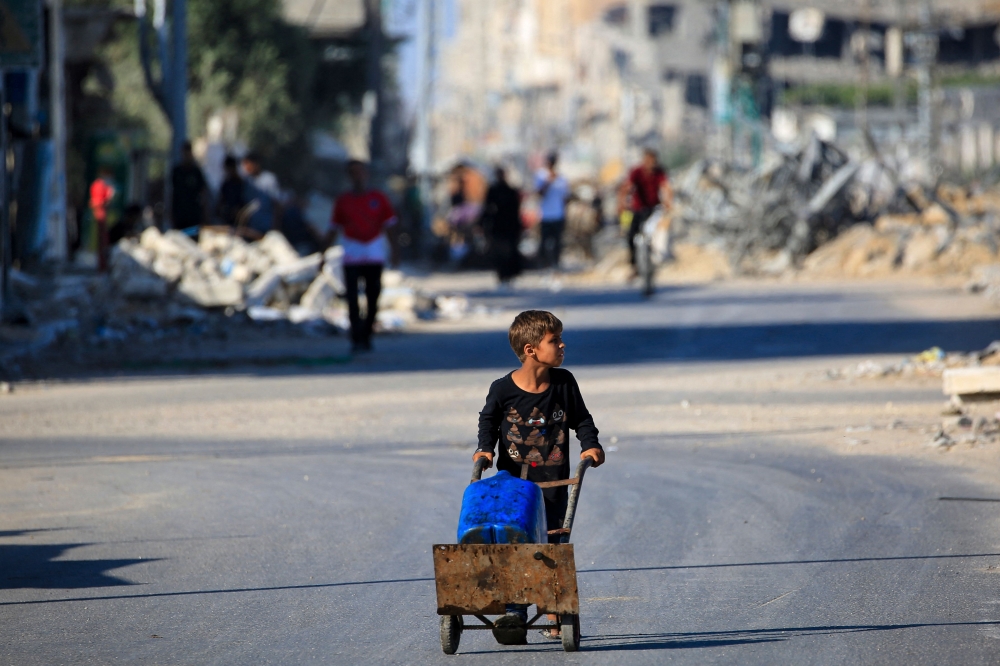 A boy carries water al-Bureij refugee camp in the central Gaza Strip on June 24, 2024. (Photo by Eyad Baba / AFP)