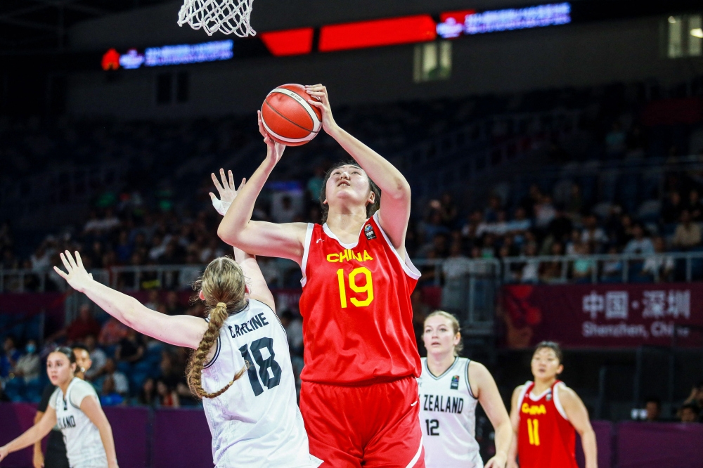 The photo taken on June 25, 2024 shows Chinese basketball player Zhang Ziyu (C) shooting past New Zealand's Elise Jayne Carline during their 2024 FIBA Under-18 Women's Asia Cup match in Shenzhen, in southern China's Guangdong province. (Photo by AFP) 