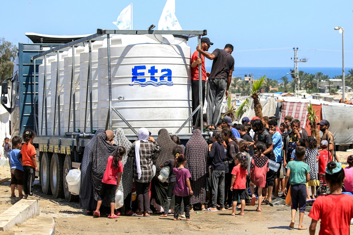 People gather to fill up their water containers from a truck loaded with water cisterns in Rafah in the southern Gaza Strip on June 25, 2024. Photo by Eyad BABA / AFP.