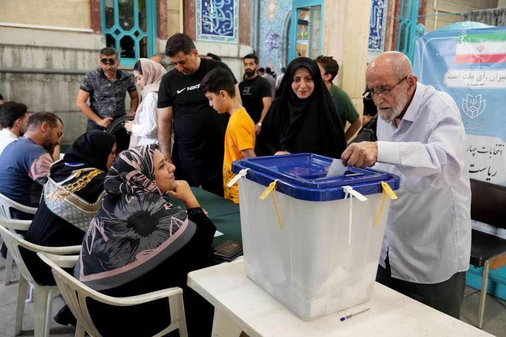 An Iranian man casts his ballot during voting at a polling station in Tehran for the Islamic republic's presidential election on June 28, 2024. (Photo by Raheb Homavandi / AFP)