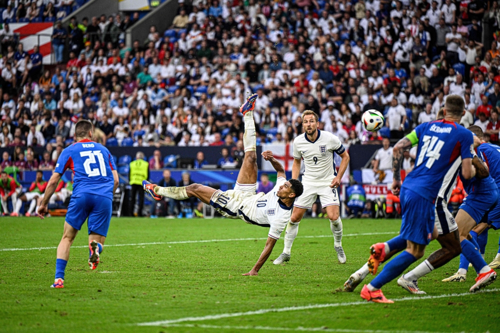 England's midfielder #10 Jude Bellingham shoots an overhead kick to score his team's first goal during the UEFA Euro 2024 round of 16 football match between England and Slovakia at the Arena AufSchalke in Gelsenkirchen on June 30, 2024. (Photo by INA FASSBENDER / AFP)
