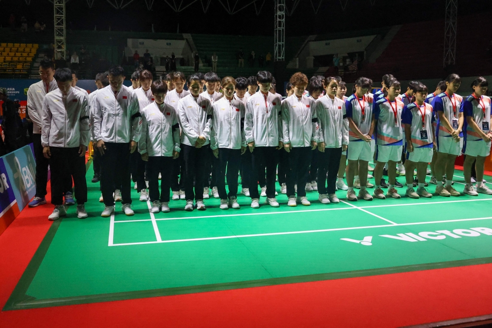 Chinese badminton players and coaches (in white jackets and black armbands), along with all players competing in the 2024 Asia Junior Championship, praying together for the late Chinese player Zhang Zhi Jie. (Photo by Handout / public relations and media division of the Indonesian Badminton Association (PBSI) / AFP)