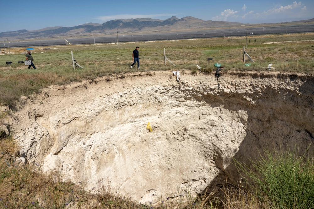 Arif Delikan, an associate professor of Konya Technical University inspects a large sinkhole in Karapinar in the central Anatolian province of Konya, on June 23, 2024. (Photo by Yasin Akgul / AFP)