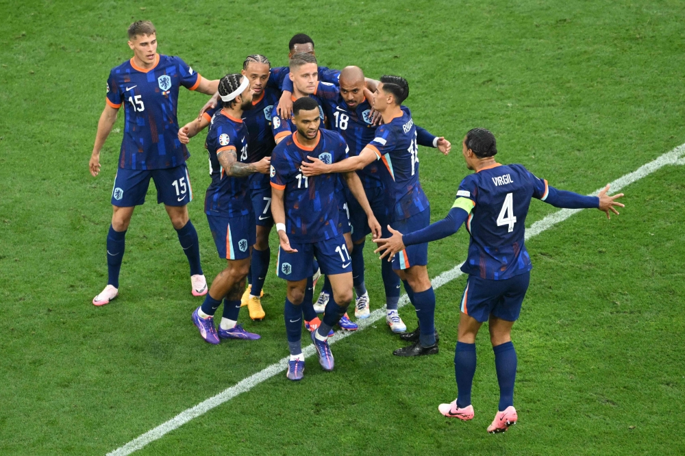 Netherlands' forward #18 Donyell Malen celebrates scoring his team's second goal with his teammates during the UEFA Euro 2024 round of 16 football match between Romania and the Netherlands at the Munich Football Arena in Munich on July 2, 2024. (Photo by Thomas Kienzle / AFP)