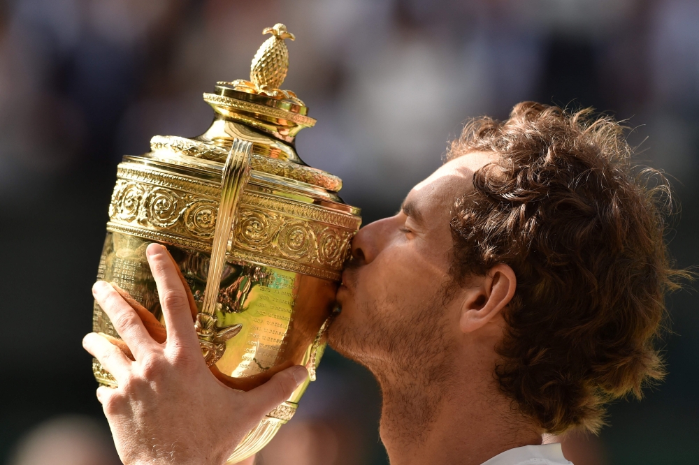 File: Britain's Andy Murray poses with the winner's trophy after his men's singles final victory over Canada's Milos Raonic on the last day of the 2016 Wimbledon Championships at The All England Lawn Tennis Club in Wimbledon, southwest London, on July 10, 2016. (Photo by Glyn Kirk / AFP) 