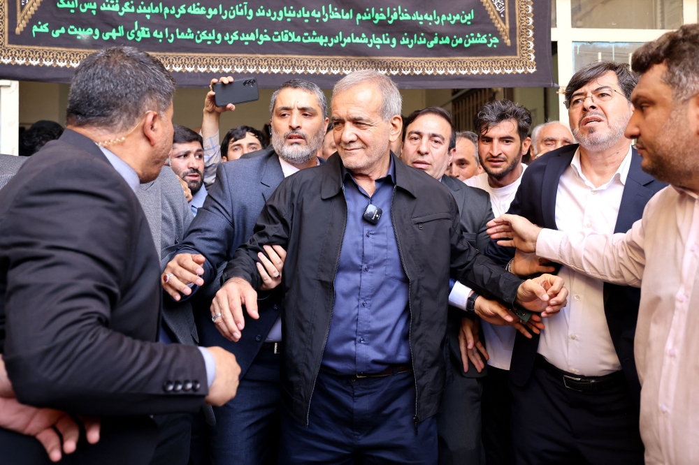 Iranian reformist presidential candidate Masoud Pezeshkian (C) leaves a polling station after voting in Tehran on July 5, 2024. (Photo by Atta Kenare / AFP)