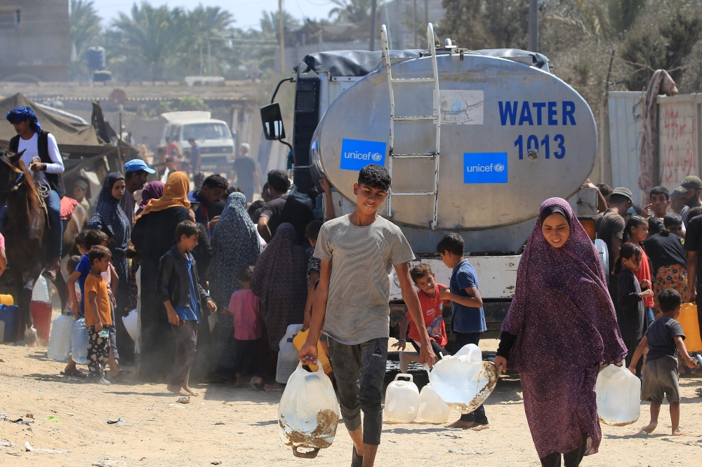 Palestinians collect water from a UNICEF tanker in Deir el-Balah in the central Gaza Strip on July 9, 2024. (Photo by Eyad BABA / AFP)
