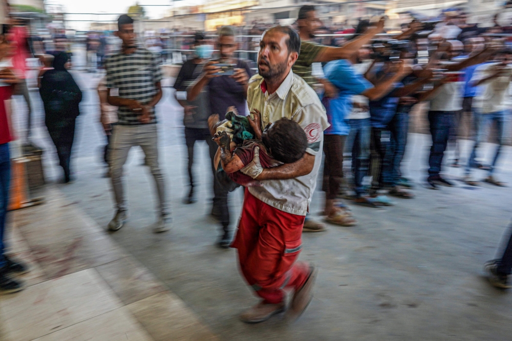 A paramedic carries a wounded child by Israeli bombardment to the emergency ward at Nassr hospital in Khan Yunis, on the southern Gaza Strip on July 9, 2024. (Photo by Bashar Taleb / AFP)