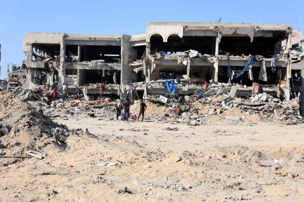 Palestinians stand in front of destroyed buildings and rubble after the Israeli military withdrew from the Shujaiya neighbourhood, east of Gaza City on July 10, 2024. (Photo by Omar Al-Qattaa / AFP)