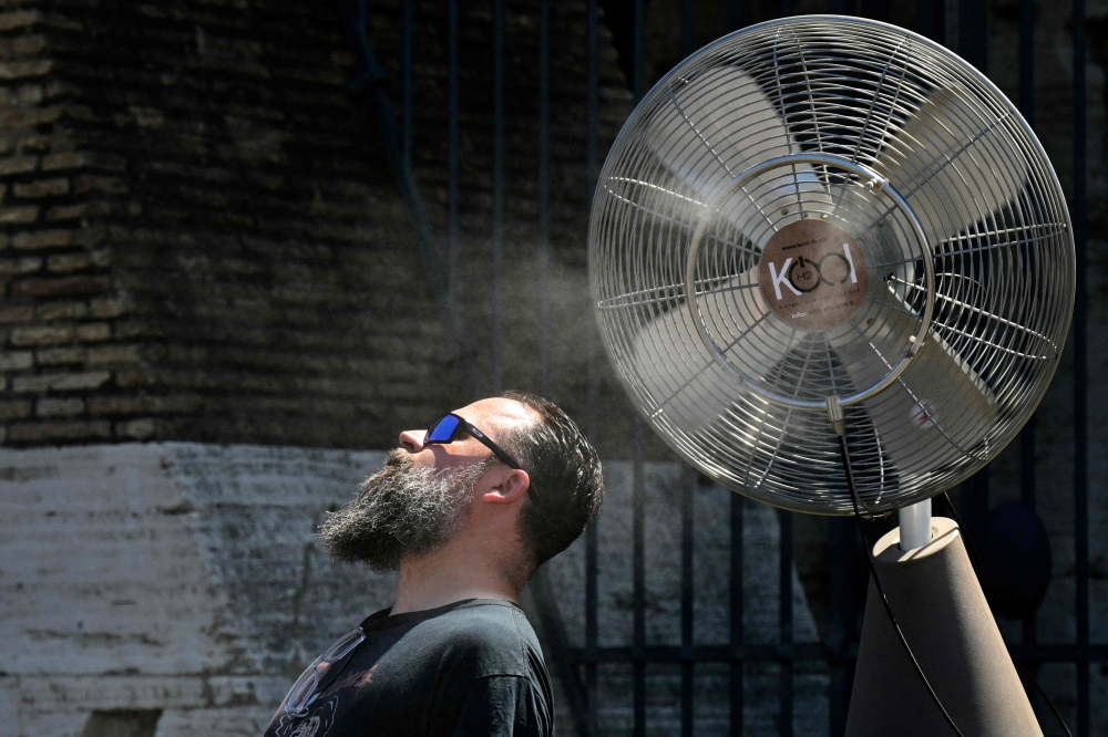 A fan sprays water along the gates of the Colosseum to refresh tourists on July 11, 2024 in Rome where temperatures reach 38 degrees celsius today. (Photo by Tiziana FABI / AFP)