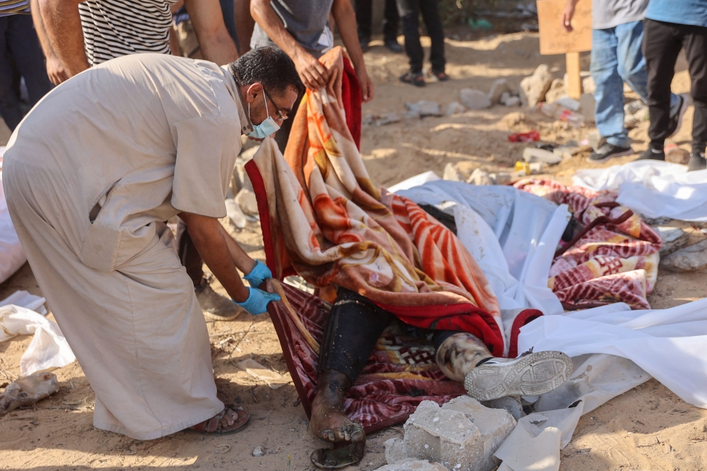 People evacuate bodies found under rubble or on the street in western Gaza City's Al-Sinaa neighbouhood on July 12, 2024. (Photo by Omar AL-QATTAA / AFP)
