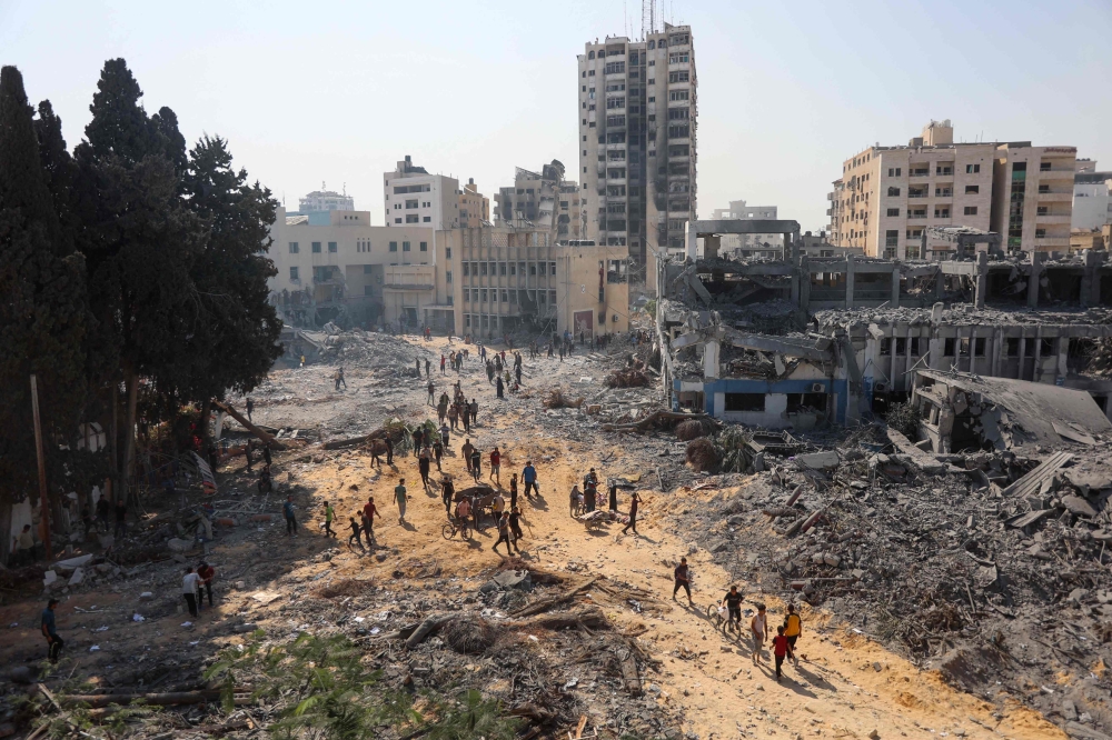 People walk on rubble at the damaged UNRWA building complex in western Gaza City's Al-Sinaa neighbouhood on July 12, 2024. (Photo by Omar Al Qattaa / AFP)