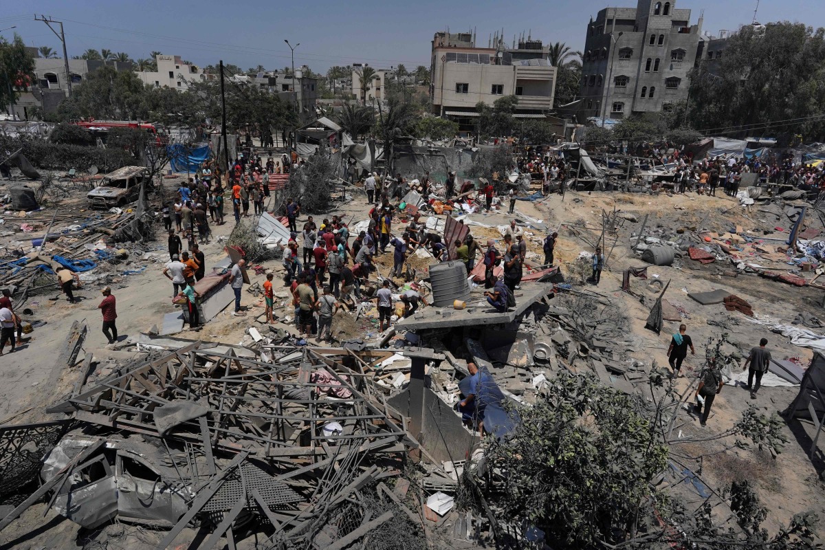 Palestinians look at the debris of destroyed tents and make shift housing structures following an Israeli military strike on the al-Mawasi camp for internally displaced people (IDP), near the city of Khan Yunis, southern Gaza Strip on July 13, 2024.(Photo by Bashar TALEB / AFP)
