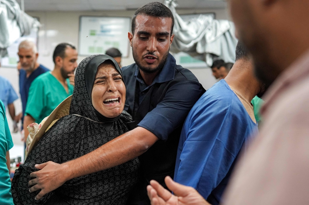 A man comforts a woman as she reacts at a trauma ward at Nasser Medical Complex in Khan Yunis in the southern Gaza Strip on July 16, 2024. (Photo by Bashar TALEB / AFP)
