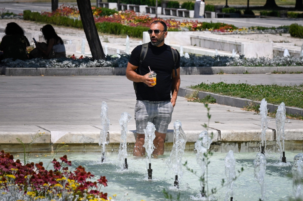 A man cools off in a fountain in the center of Sofia on July 18, 2024, as Bulgaria experiences a heatwave with temperatures reaching 42 degrees Celsius across the country. (Photo by Nikolay Doychinov / AFP)