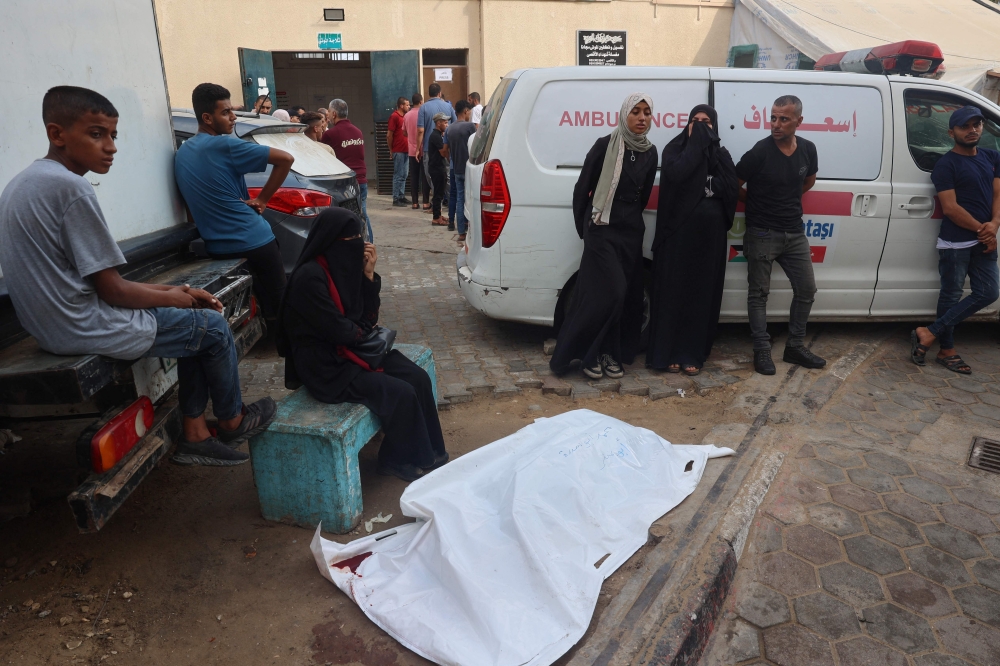 Family members surround the body of a person killed in an Israeli strike in the yard of al-Aqsa Martyrs hospital in Deir el-Balah in the central Gaza Strip on July 20, 2024, amid the ongoing conflict between Israel and the Palestinian Hamas movement. (Photo by Eyad BABA / AFP)
