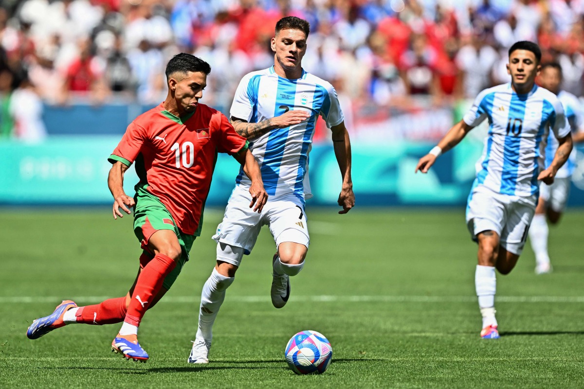 Morocco's forward #10 Ilias Akhomach (L) challenges Argentina's midfielder #07 Kevin Zenon (C) and Argentina's midfielder #10 Thiago Almada in the men's group B football match between Argentina and Morocco during the Paris 2024 Olympic Games at the Geoffroy-Guichard Stadium in Saint-Etienne on July 24, 2024. (Photo by Arnaud FINISTRE / AFP)