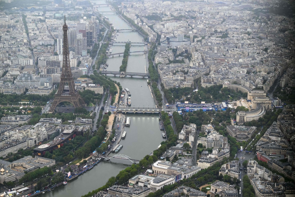 A photograph taken from an helicopter on July 26, 2024 shows an aerial view of the Eiffel Tower along the Seine river during the opening ceremony of the Paris 2024 Olympic Games in Paris. (Photo by Lionel BONAVENTURE / POOL / AFP)