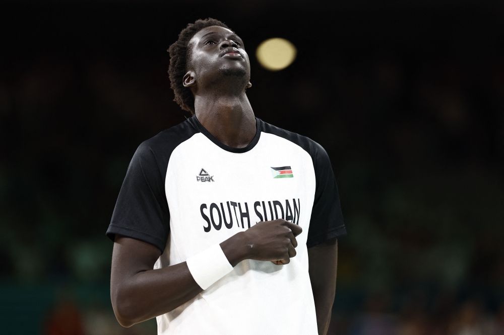 South Sudan's #10 Jt Thor stands at attention during the national anthems prior to the men's preliminary round group C basketball match between South Sudan and Puerto Rico during the Paris 2024 Olympic Games at the Pierre-Mauroy stadium in Villeneuve-d'Ascq, northern France, on July 28, 2024. (Photo by Sameer Al-Doumy / AFP)