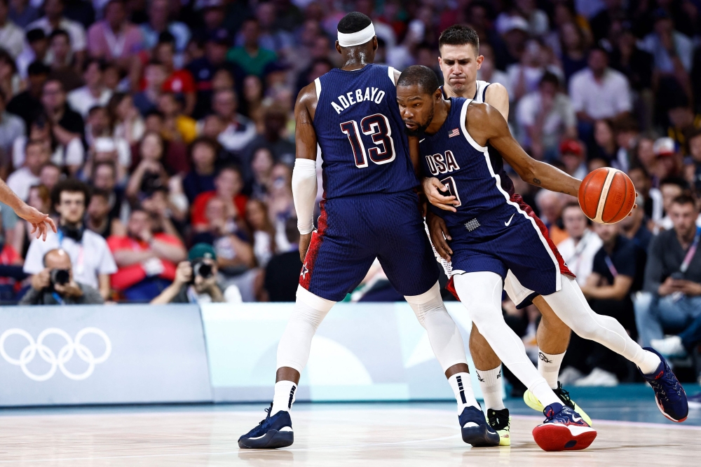 USA's Kevin Durant works around Serbia's #09 Vanja Marinkovic (Rear R) in the men's preliminary round group C basketball match between Serbia and USA during the Paris 2024 Olympic Games at the Pierre-Mauroy stadium in Villeneuve-d'Ascq, northern France, on July 28, 2024. (Photo by Sameer Al-Doumy / AFP)
