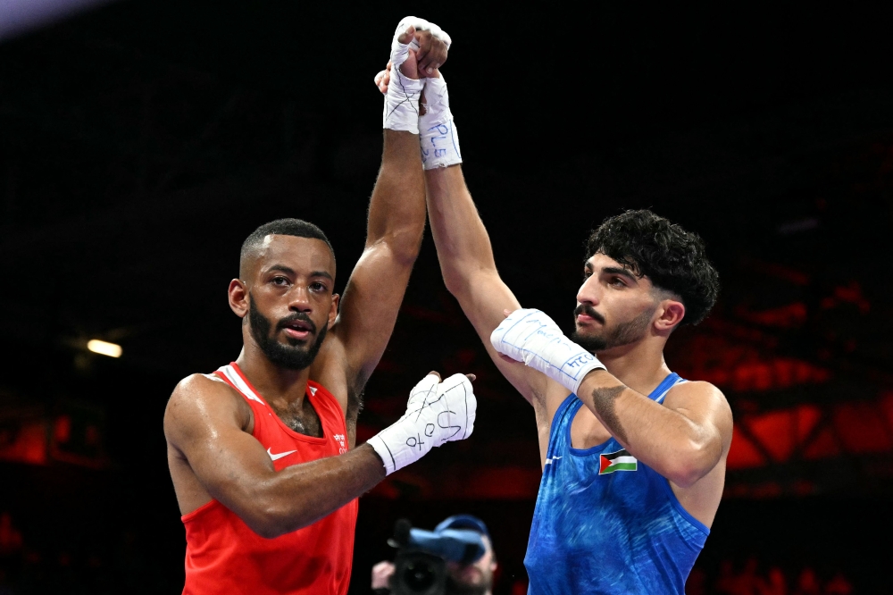 Palestinian Wasim Abusal (in blue) gestures next to Sweden's Nebil Ibrahim at the end of their men's 57kg preliminaries round of 32 boxing match during the Paris 2024 Olympic Games at the North Paris Arena, in Villepinte on July 28, 2024. (Photo by MOHD RASFAN / AFP)
