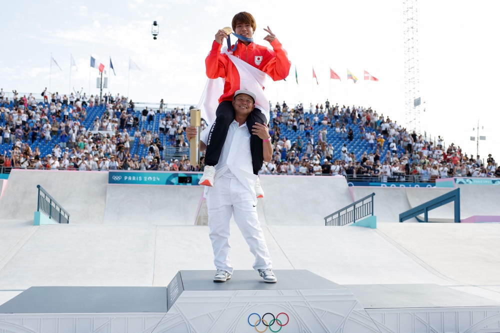 Gold medallist Japan's Yuto Horigome is carried on the podium after the victory ceremony for the men's street skateboarding event during the Paris 2024 Olympic Games at La Concorde in Paris on July 29, 2024. (Photo by Odd Andersen / AFP)