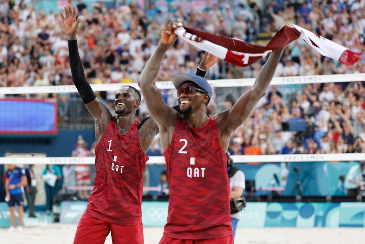 Qatar's #01 Cherif Younousse and Qatar's #02 Ahmed Tijan celebrate their victory in the men's pool A beach volleyball match between Sweden and Qatar during the Paris 2024 Olympic Games at the Eiffel Tower Stadium in Paris on July 29, 2024. (Photo by Luis Tato / AFP)