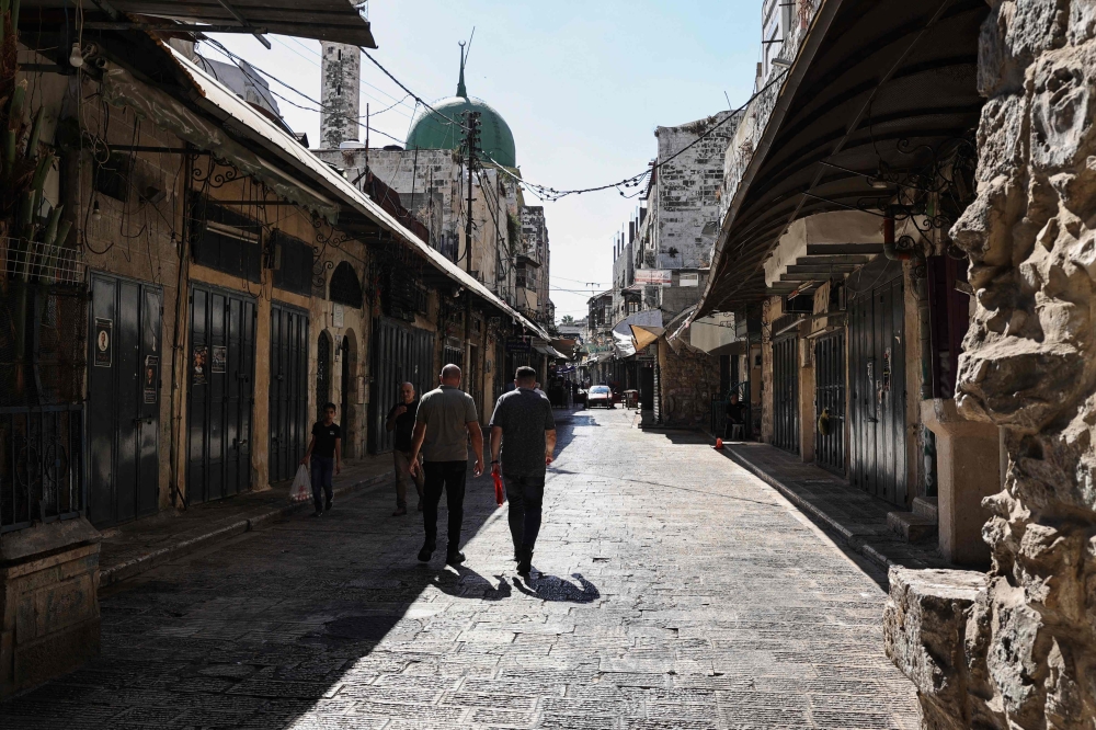 Palestinians walk through a deserted commercial area in Nablus in the Israeli-occupied West Bank during a general strike on July 31, 2024. (Photo by Zain Jaafar / AFP)